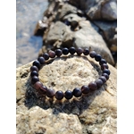 Bracelet Obsidienne Argentée 6 mm posé sur un rocher en bord de mer en Bretagne, perles sombres aux reflets métallisés pour protection profonde.