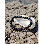 Bracelet Obsidienne Argentée présenté sur coquillage et roche marine, perles noires 6 mm pour introspection, lucidité et énergie protectrice.