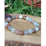 Bracelet Pierre de Lune beige multicolore sur rondin de bois, perles crème, pêche, gris doux et blanc laiteux pour intuition et équilibre émotionnel.