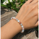 Bracelet Pierre de Lune beige multicolore porté au poignet en extérieur, bijou pastel pour douceur, féminité symbolique et nouveaux départs.