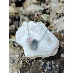 Pendentif Labradorite en forme de pointe posé dans une coquille blanche, pierre minérale grisée pour clarté intérieure et équilibre énergétique.
