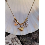 Collier doré cœur lune étoile posé sur coquillage blanc et rochers, bijou acier inoxydable avec perles blanches et strass lumineux.