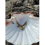 Collier acier inoxydable doré présenté sur grand coquillage blanc, breloques lune, étoile, cœur et perles dans un décor marin naturel.