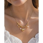 Collier doré cœur lune étoile porté au cou avec haut blanc, perles décoratives et pendentifs fins pour un style céleste élégant.