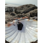 Collier Obsidienne noire sur coquillage face aux rochers bretons, pendentif sombre pour recentrage et énergie protectrice.