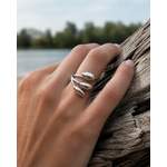 Bague argentée triple goutte portée au doigt près du bois, bijou ajustable lumineux au style fluide et élégant.