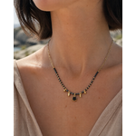 Collier doré Onyx porté au cou en lumière naturelle, pierres noires, strass central et chaîne acier inoxydable.