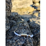Bracelet Améthyste breloque longue posé sur rocher côtier, perles mauves et détails dorés pour clarté et douceur.