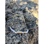 Bracelet Améthyste breloque dorée sur roche en bord de mer, perles lilas facettées et acier inoxydable pour sérénité.