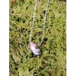 Pendentif Rhodonite naturelle en forme de pointe sur décor minéral, nuances roses et sombres pour équilibre intérieur.