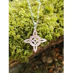 Pendentif Nœud de Sorcière argenté photographié sur mousse bretonne, symbole fin au style ésotérique et naturel.