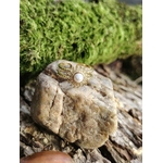 Bague motif Soleil sur pierre claire devant mousse verte, cabochon blanc nacré et double anneau doré ajustable.