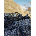 Bague ajustable cabochon nacré sur roche du bord de mer breton, motif solaire doré en lumière naturelle.