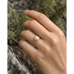 Bague Soleil portée au doigt en extérieur, motif rayonnant doré avec cabochon nacré pour une pose naturelle.