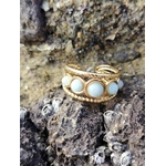 Gros plan sur bague réglable Amazonite dorée parmi roches et coquillages, pierres bleu-vert associées à la communication douce.