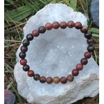 Bracelet Jaspe Polychrome posé sur une druse blanche en extérieur, perles multicolores aux nuances terre et feu, pour protection et stabilité émotionnelle.