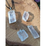 Quatre pendentifs Calcite Optique sur tranche de bois, formes brutes transparentes avec bélières argentées pour recul et vision intérieure.