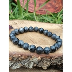 Bracelet Larvikite 8 mm posé sur tranche de bois en extérieur, perles gris charbon, concentration et recul intérieur.