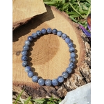 Bracelet Tanzanite 6 à 7 mm sur rondin de bois au soleil, perles bleu lavande pour intuition et transformation spirituelle.