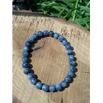 Bracelet Tanzanite naturelle posé sur bois clair en extérieur, perles bleutées pour clarté mentale et communication authentique.