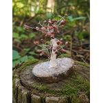 Petit arbre décoratif en Rhodonite baroque dans un décor naturel, lumière douce et énergie de compassion sans promesse miracle.