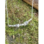 Gros plan sur les pierres de Labradorite du collier, nuances translucides et éclats bleus sur tapis de mousse.