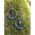 Boucles doreilles créoles cyanite posées sur mousse en forêt, nuances bleues pour apaisement et expression juste.