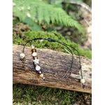 Bracelet cordon noir avec étoile dorée et perles facettées crème, ambrées et rosées, présenté à plat avec ses liens réglables.