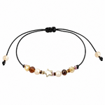 Bracelet étoile dorée porté au poignet en lumière naturelle, cordon noir ajustable et petites perles lumineuses aux tons doux.