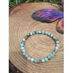 Bracelet larimar 6 mm sur bois en décor naturel, perles bleu turquoise, bleu pastel, blanc nuancé et inclusions brun gris, lâcher-prise, stabilité émotionnelle et sérénité