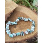 Bracelet larimar baroque sur tranche de bois naturel avec feuillage vert, éclats bleu ciel, blanc et brun marbré pour apaisement du ressenti et fluidité émotionnelle