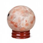 Sphère en Pierre de Soleil naturelle (héliolite) sur socle en bois, fond blanc neutre, reflets nacrés orangés et inclusions cuivrées — symbole de joie, d’optimisme et d’énergie positive.