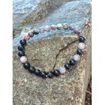 Bracelet en tourmaline multicolore posé à plat sur rocher, perles pastel et noires en 6 mm pour stabilité et bouclier énergétique