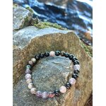Bracelet tourmaline multicolore rose, violet et noir sur rocher près de l’eau, pierre naturelle liée au courage et à la protection