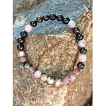 Bracelet tourmaline multicolore sur rocher en lumière naturelle, perles rose-violet et noires pour apaisement, ancrage et confiance