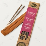 Boîte d’encens organique « Smudge Sticks – Descarga Total / Total Discharge » (AUM), à côté d’un porte-encens en bois avec deux bâtons d’encens non allumés — visuel d’ambiance, porte-encens non inclus, packaging rose/beige sur fond clair.