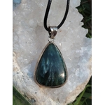 Pendentif séraphinite goutte en argent 925 sur cordon noir, posé sur pierre irisée, bijou en pierre naturelle associé à la douceur émotionnelle, à l’harmonie intérieure et au calme du cœur.
