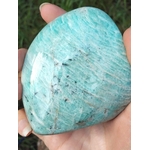 Forme libre Amazonite tenue en main, gros plan sur les marbrures bleu-vert et les inclusions naturelles de la pierre.