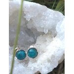 Boucles d’oreilles apatite bleue cabochons ronds en argent 925, posées sur druse de quartz blanc en extérieur (brin d’herbe au premier plan) — clarifie les idées et renforce l’expression créative.