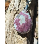 Pendentif tourmaline rose naturelle en goutte avec bélière en acier inoxydable, posé sur tronc de bois avec cordon noir visible, bijou en pierre naturelle lié à la tendresse, au calme affectif et à l’harmonie intérieure.