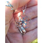 Pendentif graine de vie en argent 925 tenu dans la main, motif de géométrie sacrée à sept cercles bien visible