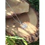 Pendentif graine de vie argenté sur rondin de bois, symbole de géométrie sacrée pour harmonie visuelle et style spirituel