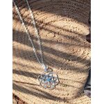 Pendentif graine de vie en argent 925 sur chaîne posé sur bois au soleil, bijou de géométrie sacrée au motif à sept cercles