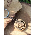Porte-clés en bois gravé triquetra celtique et phases de lune, posé sur rondin