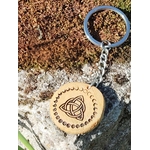 Porte-clés en bois rond gravé triquetra celtique et phases de lune, posé sur mousse et rocher