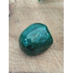 Malachite roulée vert profond sur planche de bois — veines naturelles, protection, transformation, équilibre émotionnel.