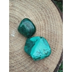 Deux pierres de malachite polies aux veines vertes, posées sur tranche de bois — ancrage doux et harmonie émotionnelle