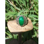 Bague artisanale en argent 925, cabochon de malachite posée sur champignon, herbes en arrière-plan — protection et transformation intérieure (lithothérapie)