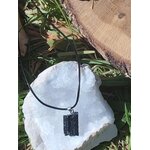 Pendentif tourmaline noire brute sur une géode blanche, pierre naturelle reliée à l’ancrage, à la purification énergétique et à la stabilité intérieure.
