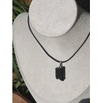 Pendentif en tourmaline noire brute sur cordon noir, présenté sur fond clair, bijou en pierre naturelle évoquant la force intérieure, l’équilibre et l’ancrage profond.